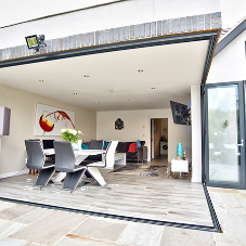 Glass bi-folding doors by Sky Bespoke Glass integrate into indoor and outdoor spaces
